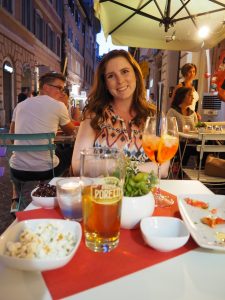 Caitlin at a cafe in Rome with an aperol spritz