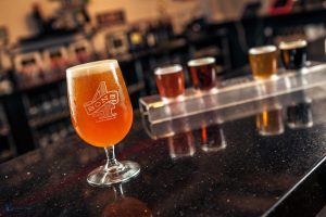 A pint of beer with a tasting flight in the background