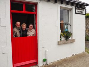 Caitlin, Tucker, and Biddy looking through the red door of the cottage.