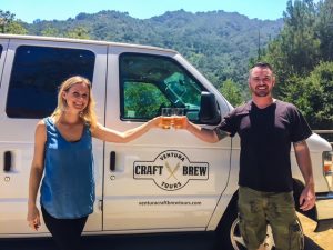 Two people cheersing a beer in front of a van.