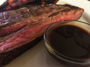 Sliced steak with whiskey steak sauce on the side.