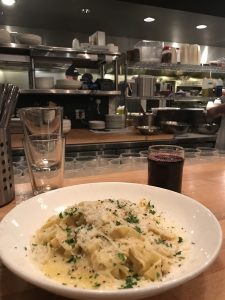 A plate of pasta with kitchen in the background.