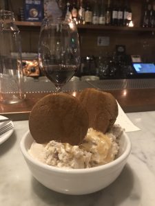 A bowl of ice cream topped with two cookies.