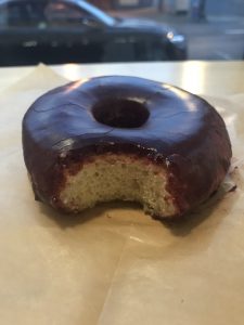 A purple donut with a bite taken out of it.