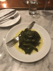 Braised greens and olive oil on a small white plate.