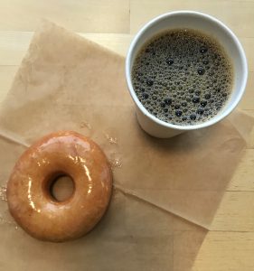 A glazed donut and cup of coffee.