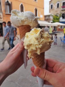 Two hands holding gelato cones in Italy.