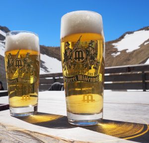 Two glasses of beer with mountains in the background.