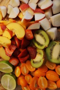 Cutting board full of raw fruits.