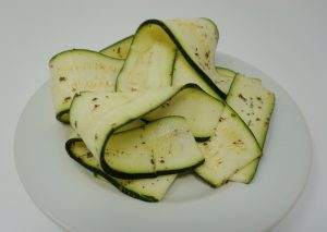 White plate with ribbons of zucchini.