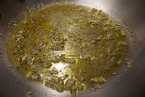 Frying pan with olive oil, garlic, salt, pepper, and lemon juice.