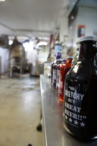 Growlers of beer with the brewery in the background.