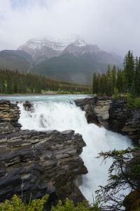 A large waterfall with mountains in the background.