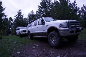 Two trucks parked in the forest.