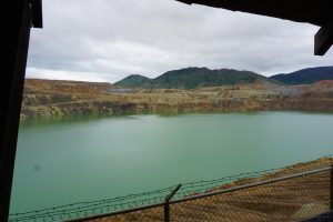 A large turquoise water reservoir filled with toxic chemicals from mining.