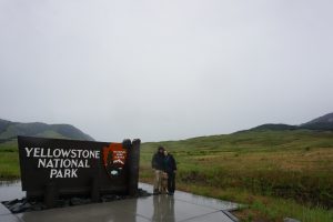 Tucker, Caitlin, and Oakley standing next to the Yellowstone National Park sign.