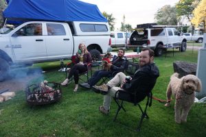 Three adults and two dogs sitting by the campfire.