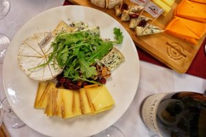 A plate of cheese alongside a bottle of wine.