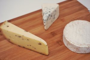 A wooden board with three types of cheese.