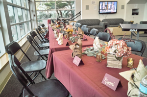 A long table decorated with flowers, candles, and other Thanksgiving decorations.