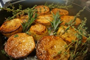 A cast iron pan with potatoes and herbs.