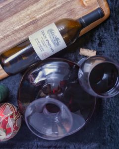 Bottle of wine in a decanter with a glass and the empty bottle.