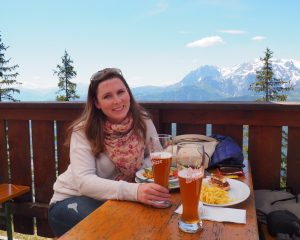 Caitlin sitting with a beer with a mountain scape in the background.