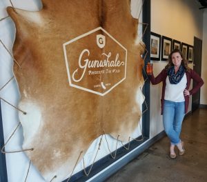 A hide with Gunwhale's logo with Caitlin standing next to it.