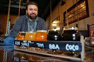 A flight of beer with head brewer Tim in the background