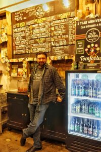 Tim Kazules standing in front of his tasting room menu