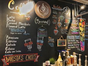 A blackboard filled with text and illustrations for coffee drinks.