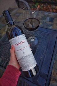 Caitlin holding the DAOU bottle next to a glass of the Cabernet Sauvignon.