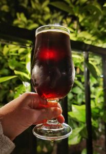 A glass of Enegren Baltic Maple Porter held up to the light.