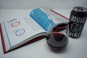 Can of wine, glass of wine, and book in the background.