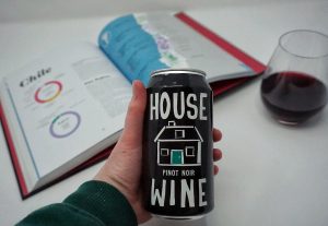 Caitlin holding a can of House Wine Pinot Noir