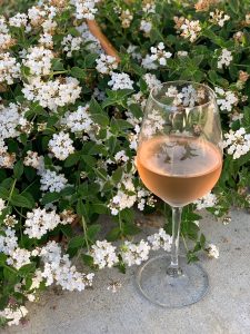 Glass of Rosé with reflection of flowers in the glass.