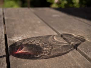 Reflection of a wine glass on a wood table.