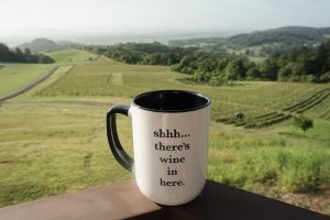 Coffee mug that reads "shhh...there's wine in here", with Willamette Valley in the background.