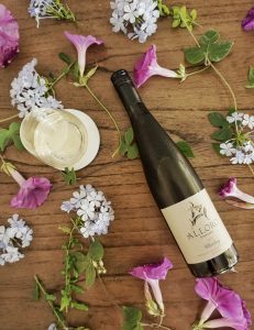 Bottle of Alloro Vineyard Riesling surrounded by flowers.