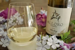 Glass of Alloro Riesling with bottle in the background.