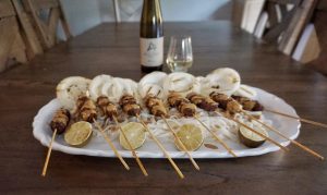 Plate of kebobs with Alloro wine in the background.