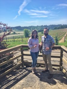 Caitlin and Tucker standing at Lenne Estate with a bottle of Pinot Noir that they will take home to age for a few years.