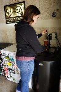 Caitlin pouring a pint of beer from the kegerator.