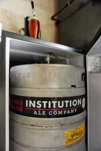 Photo of keg inside keg fridge with fresh beer on top.