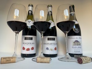 Three bottles of Beaujolais wine with three classes of wine and the corks. 