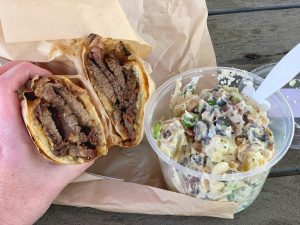 Close up shot of a tri tip sandwich and potato salad from Los Olivos Grocery